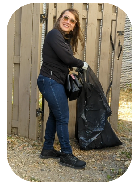 Volunteer holding garbage bag cleaning yard