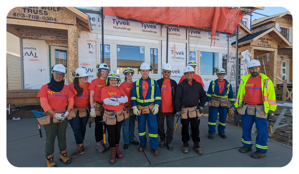 Group of NOVA volunteers with toolbelts in front of a new home construction